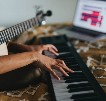 Hands on music keyboard also holding guitar