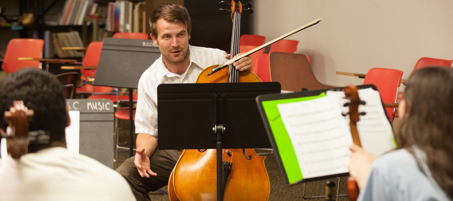 Music teacher with cello instructs students